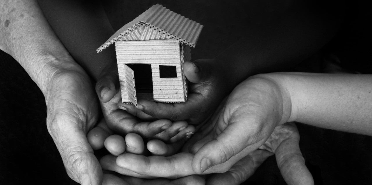 A picture of many hands holding a paper house