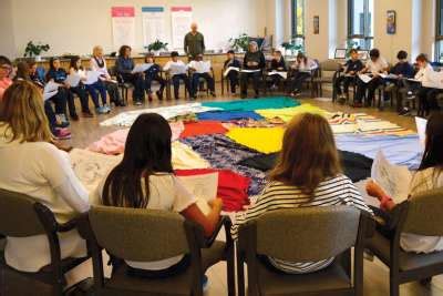 People in chairs in a circle with blankets on the floor preparing for a Blanket Exercise